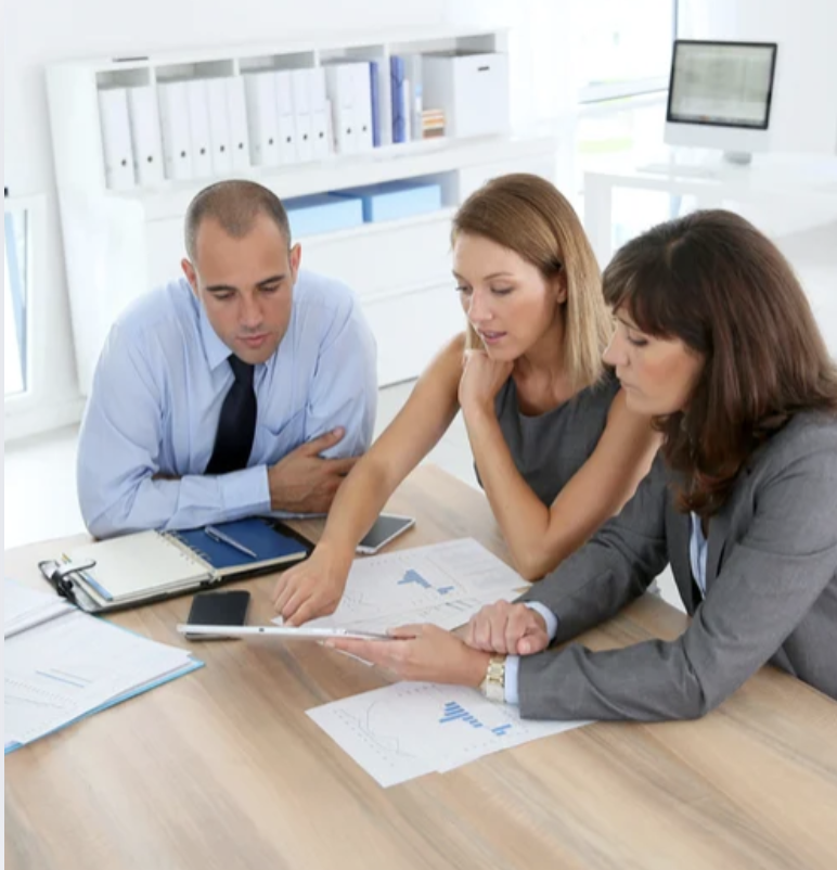 Group of people reviewing work around a table