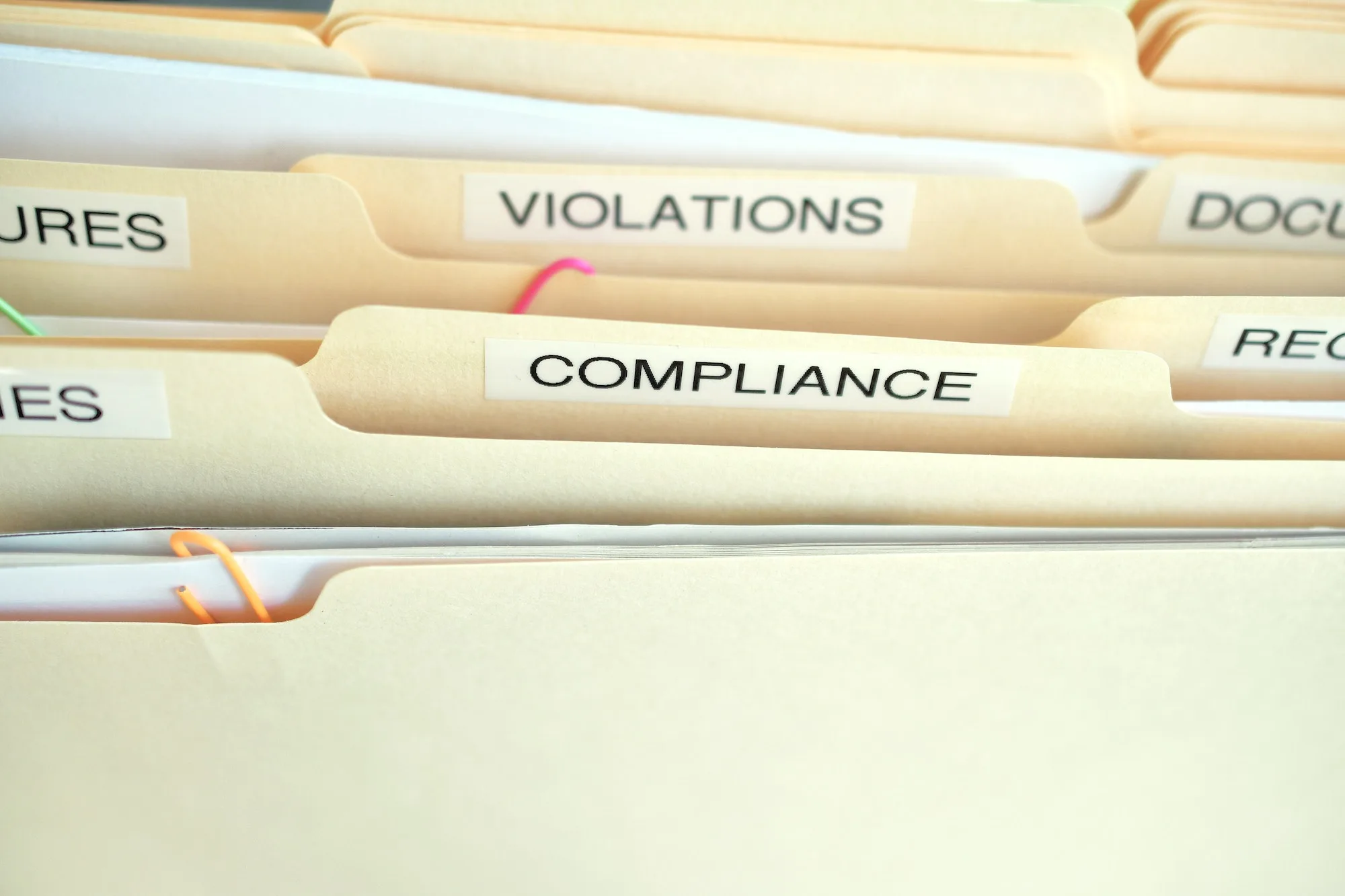 Compliance in the workplace. Folders labeled Compliance, Violations in focus.