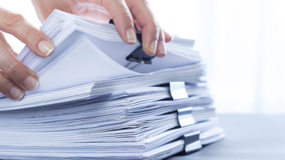 a person holding a stack of papers on top of a desk