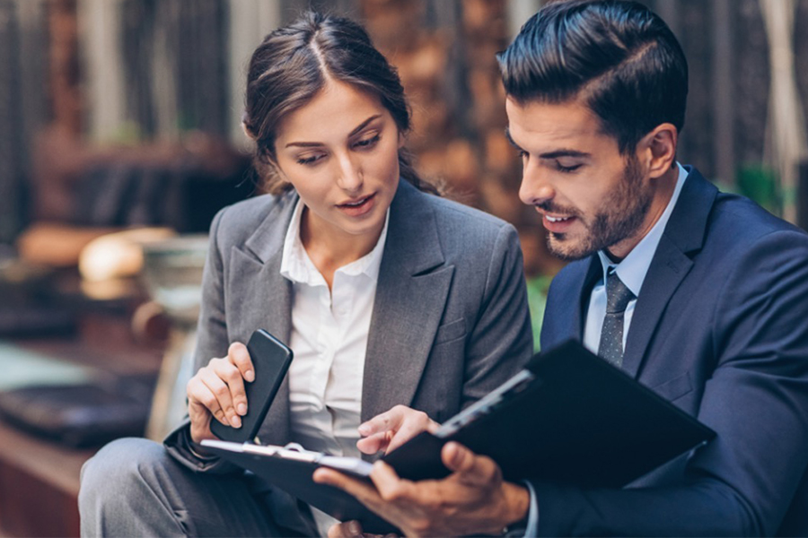 Two people in business attire looking at documents