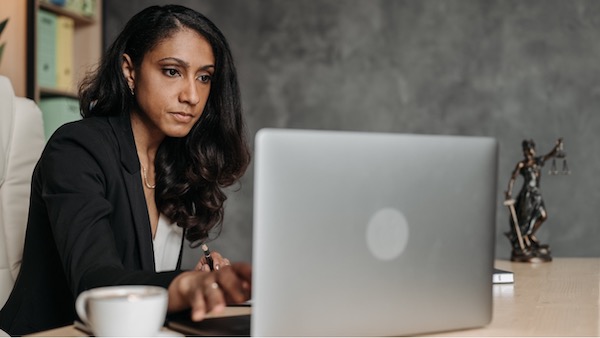 A person in a business suit sitting at a desk with a laptop