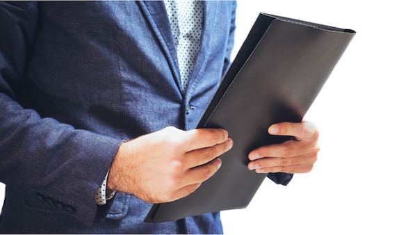 A person in a suit holding a folder