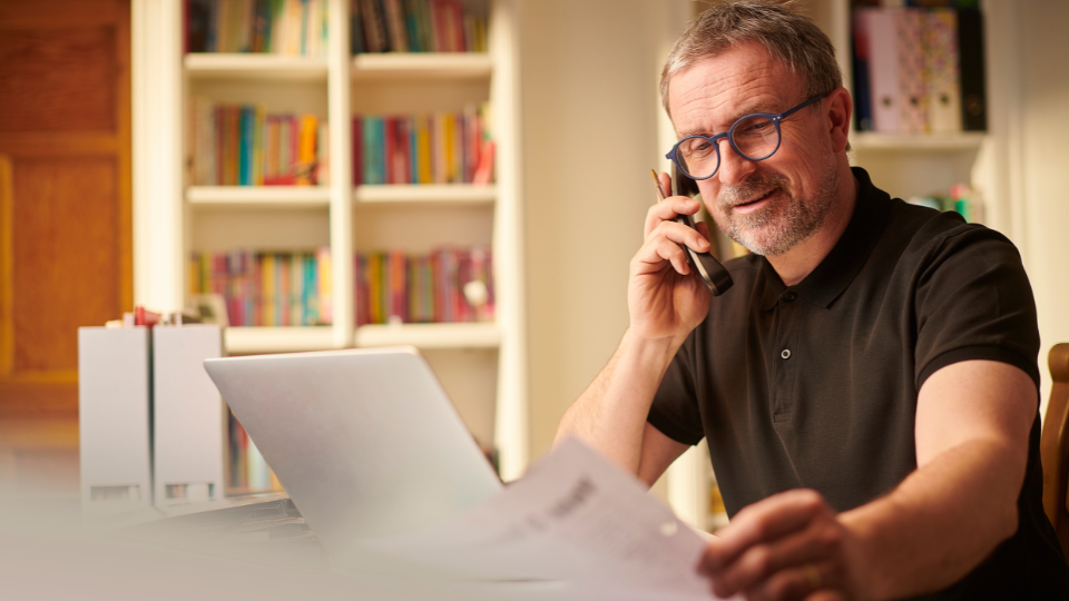 a person is sitting at a desk with a laptop and talking on the phone