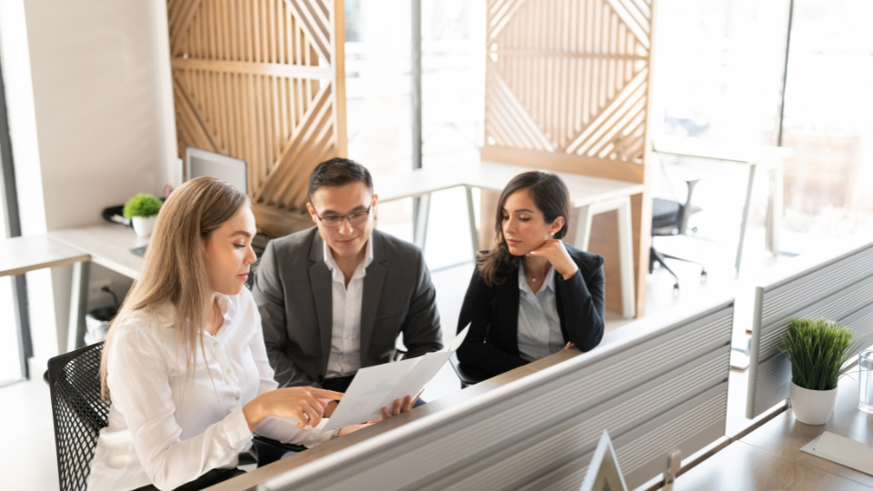 Three people sitting at a desk in an office