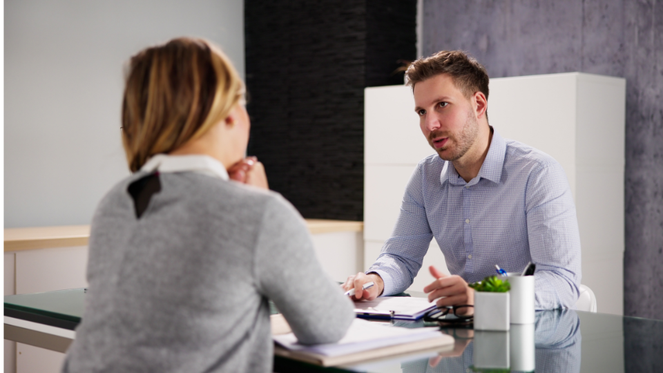 a person sitting at a desk talking to another person