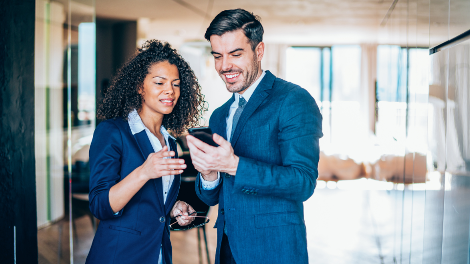 Two people in business attire looking at their cell phones